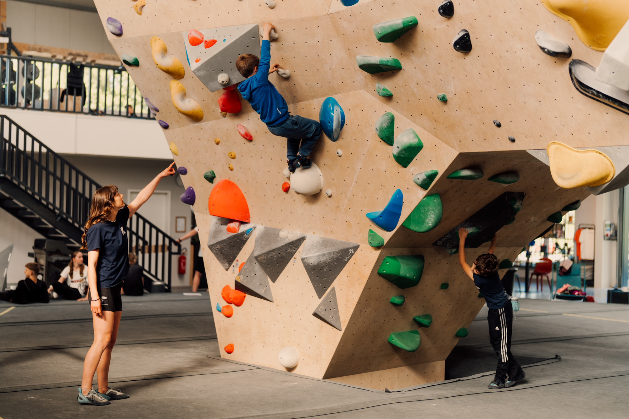 child climbing with trainer spotting